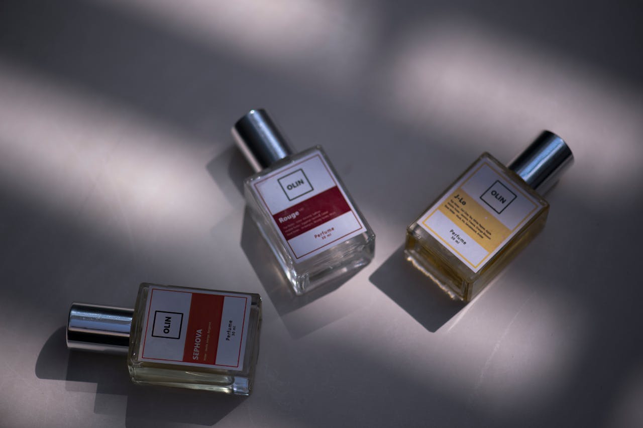 gallery-5 A still life shot of three elegant perfume bottles on a flat surface under soft lighting.