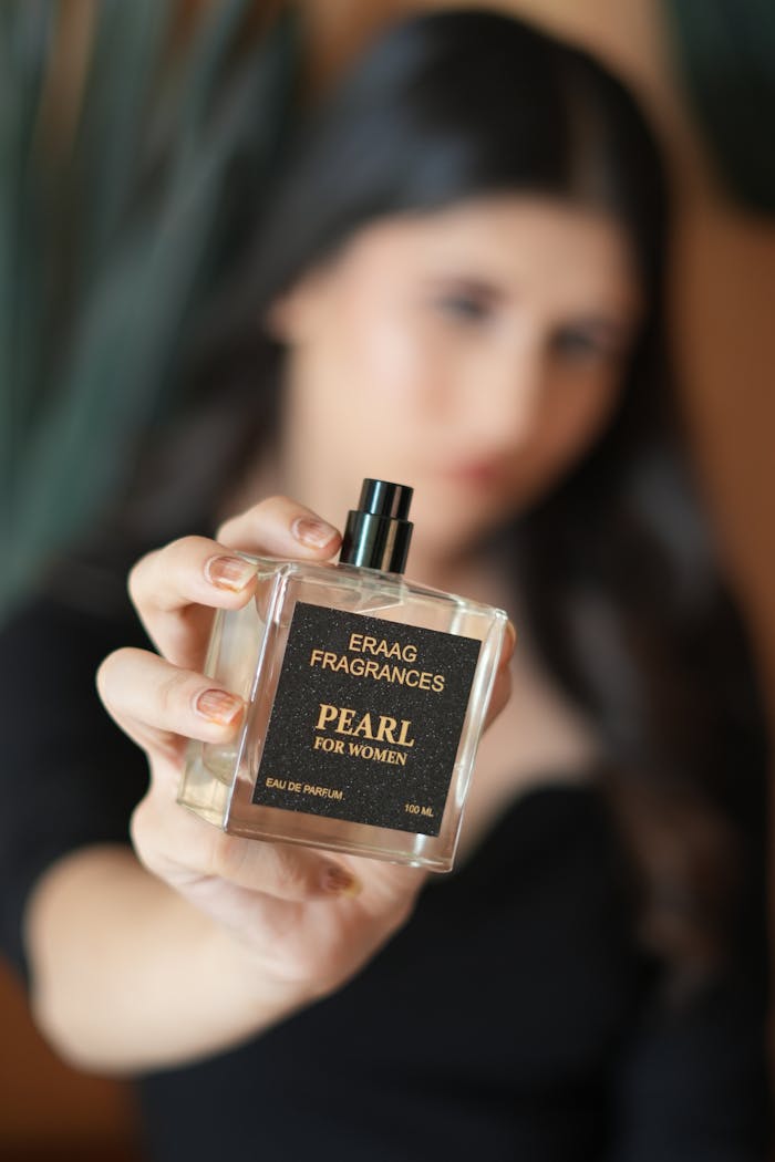 gallery-3 Elegant close-up of a woman holding a luxury perfume bottle labeled 'Pearl' by Eraag Fragrances.