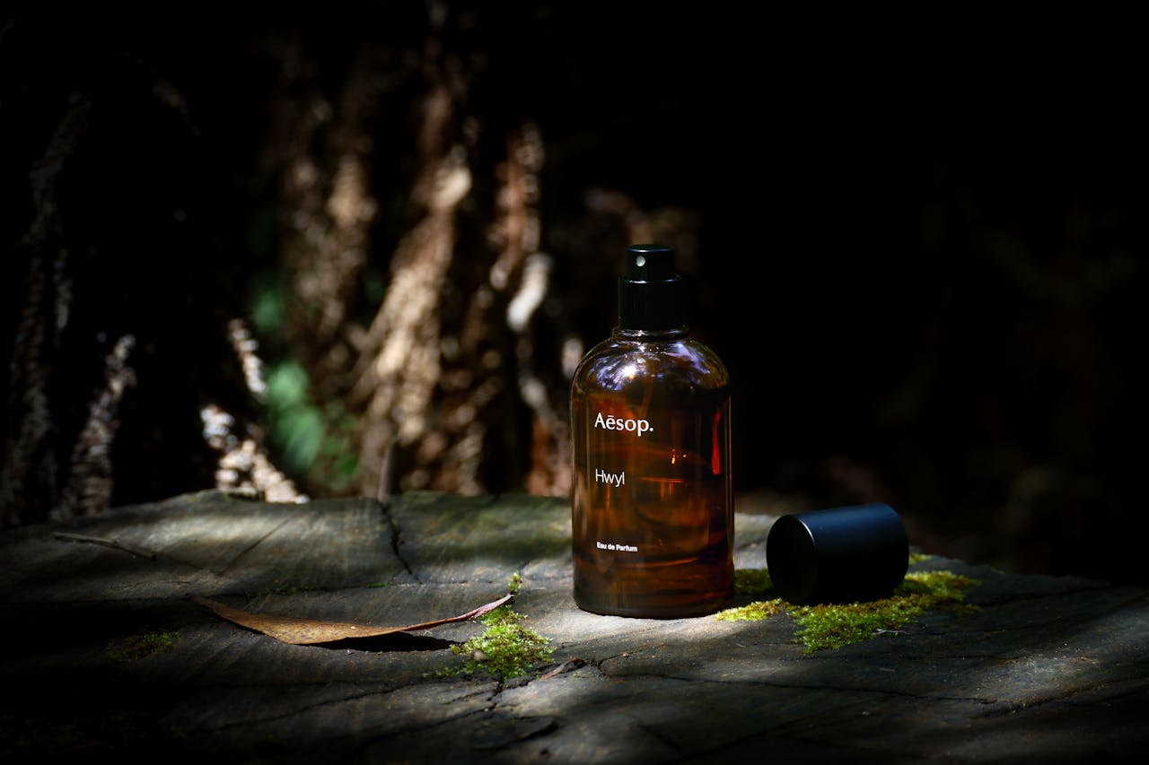 gallery-4 Aesop Hwyl perfume bottle set on a mossy tree stump in natural forest light.